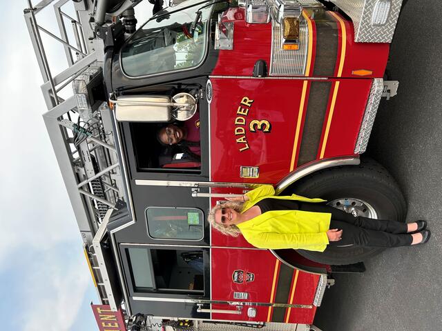 a young woman in a fire truck with another woman standing outside in a yellow and black oufit