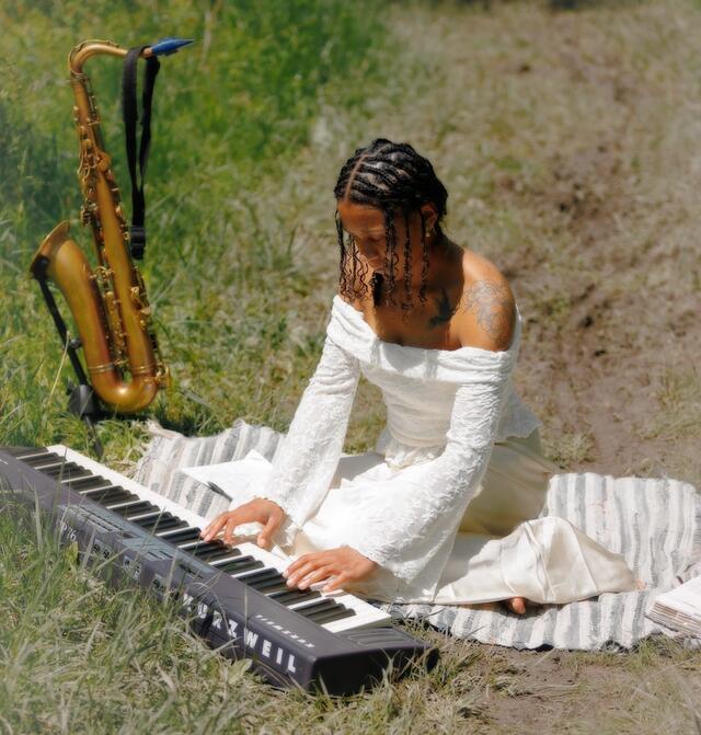 kamille austin playing keyboard with saxophone beside her