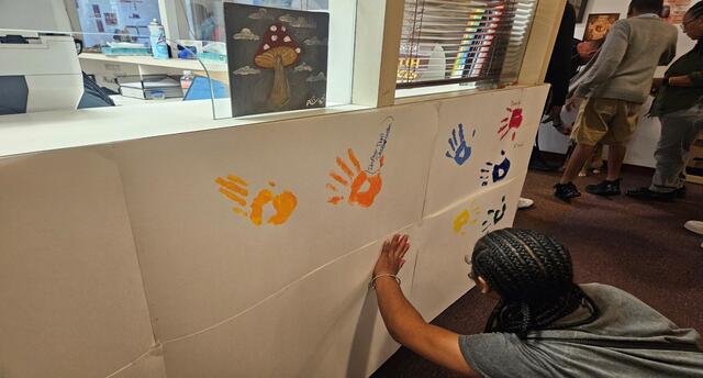 a young person puts their painted handprint on a wall in the health clinic at central state university
